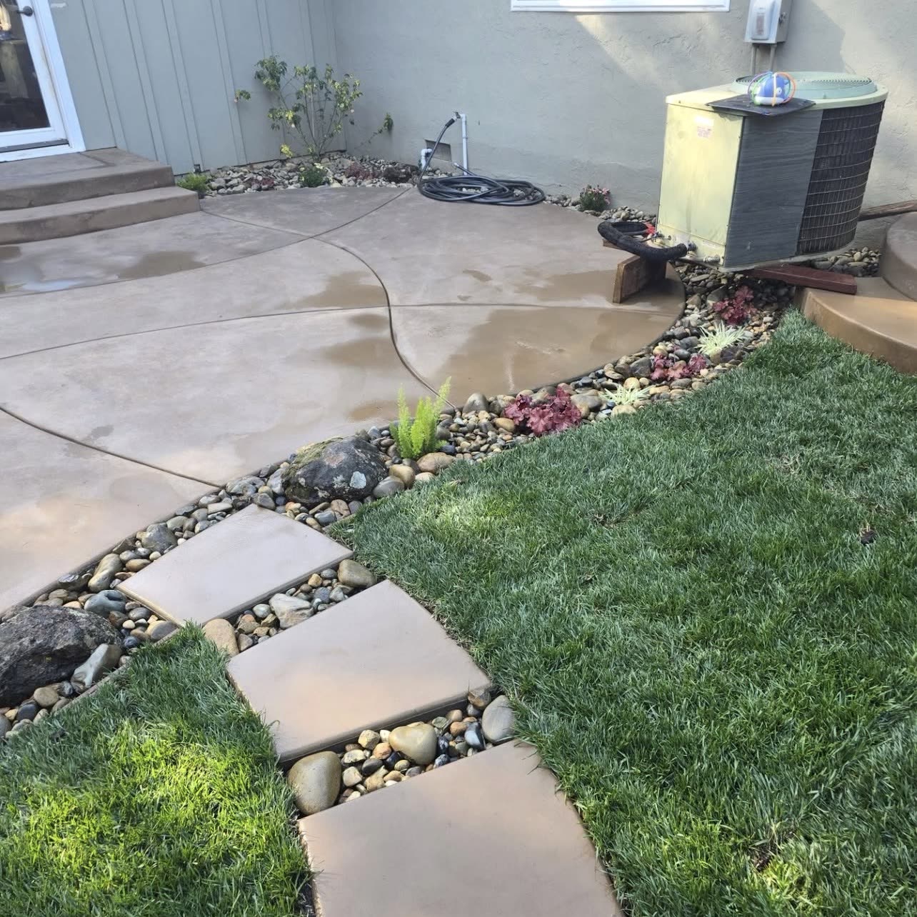 Stained and scored concrete patio with steppers set in river rock