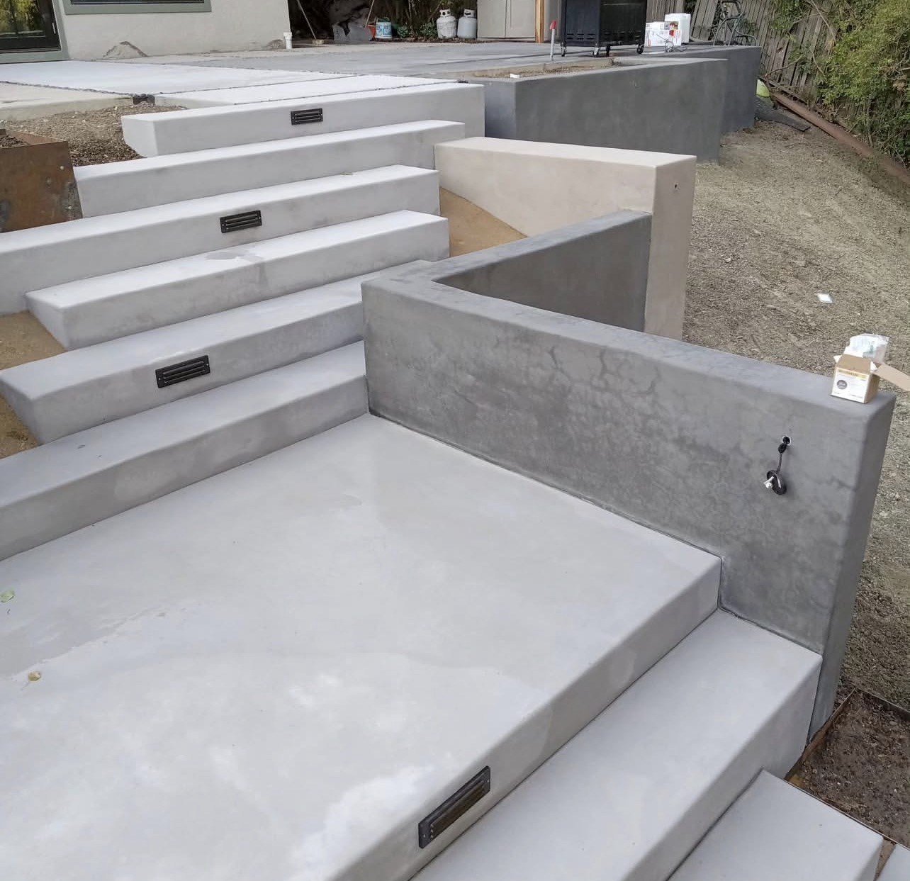 Poured concrete steps and landings with recessed step lights and a board-formed seat wall