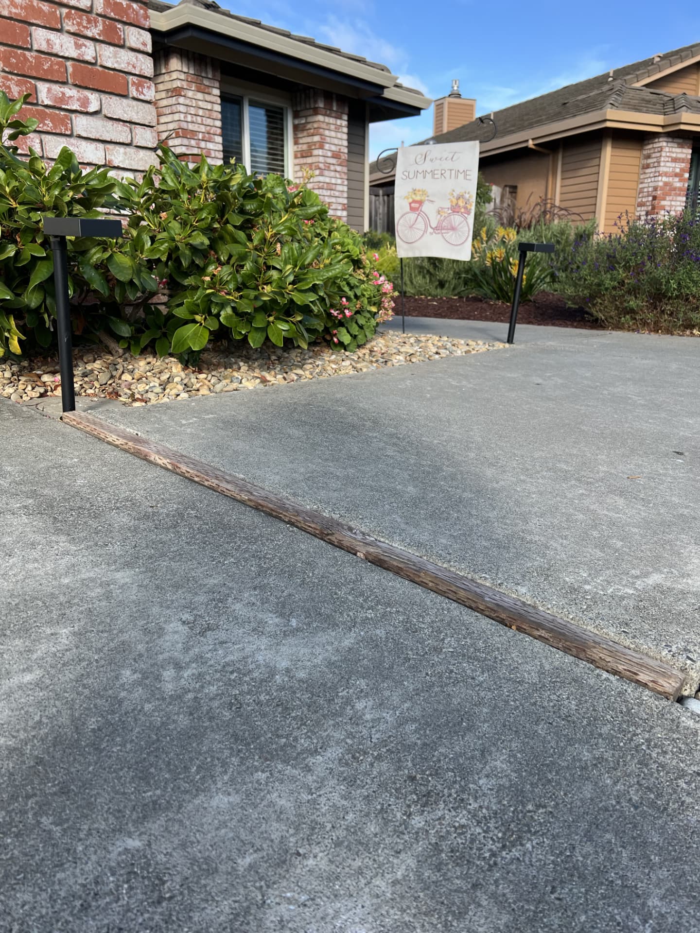 Raised wood expansion joint creating a trip hazard between two driveway slabs